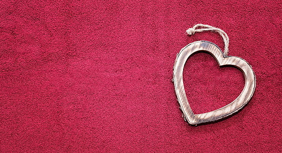 heart-shaped silver-colored pendant on top of red textile thumbnail
