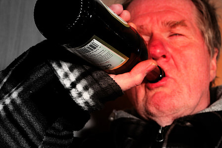 man wearing black zip-up jacket drinking on black and white labeled glass bottle thumbnail
