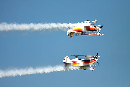 two multicolored biplanes travelling under clear blue sky thumbnail