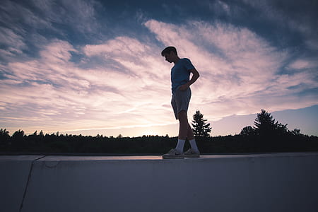 man in blue top standing on railing during sunset thumbnail