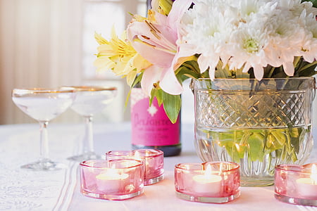 selective focus photography of tealight votive candles on table near floral arrangement and wineglasses thumbnail