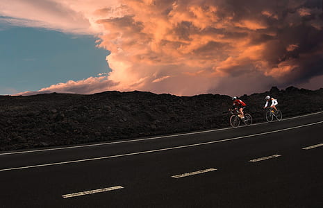 two person riding road bikes near road during daytime thumbnail