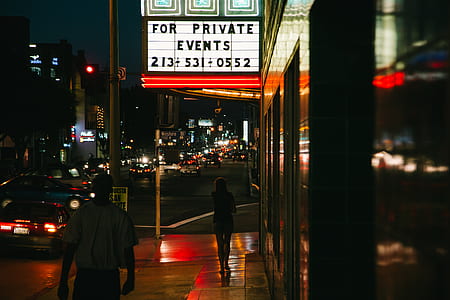 woman walking near black concrete building near signage thumbnail