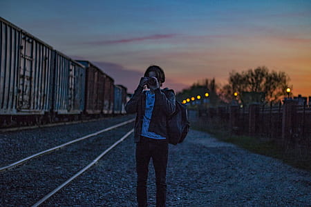 Man Wearing Brown Jacket With Backpack Taking Photo during Golden Hour thumbnail
