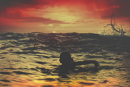 silhouette photo of boy swimming on body of water thumbnail