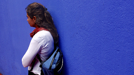photo of woman's wearing white crew neck long sleeve shirt leaning on blue painted wall thumbnail