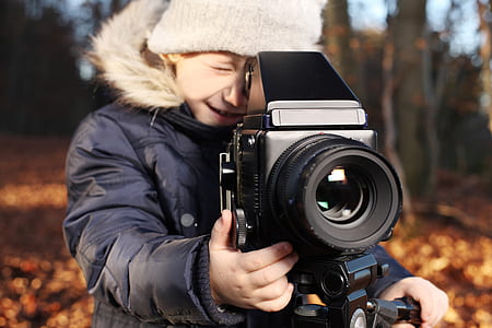 selective focus photography of boy taking a photo thumbnail
