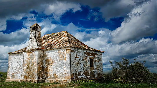 brown concrete house under blue and white clouds thumbnail