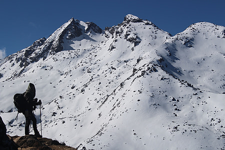 traveler wearing outfit holding stick beside mountain at daytime thumbnail