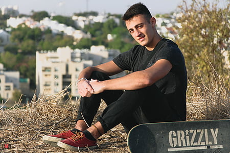 man in black crew-neck t-shirt and black jeans beside black skateboard thumbnail