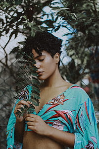 woman wearing blue and red crop shirt holding plant thumbnail
