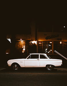 classic white Chevrolet Impala hardtop coupe at night parked near concrete building thumbnail