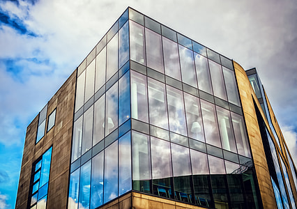 low angle of curtain wall building under white clouds at daytime thumbnail