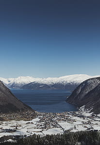 aerial photography of mountain range beside sea under clear blue sky thumbnail