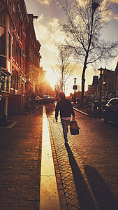 person in black jacket and blue pants carrying black and brown bag thumbnail
