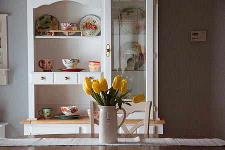 yellow tulips in white ceramic vase on brown wooden dining table thumbnail