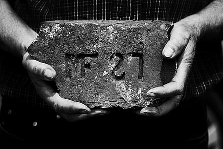 grayscale photography of person holding concrete brick thumbnail