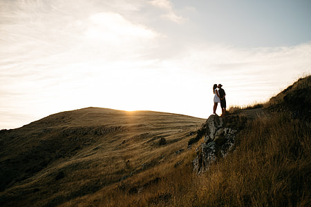 couple kissing on cliff under cloudy sky thumbnail