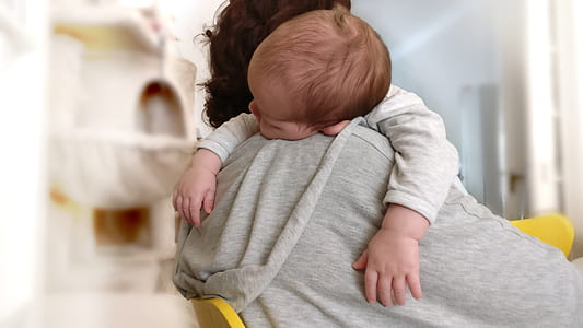 person carrying baby while sitting on chair thumbnail