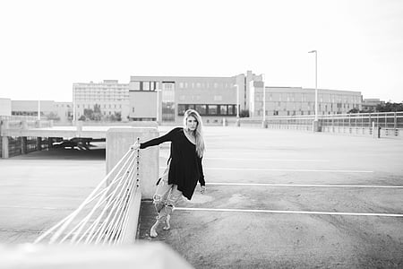 grayscale photography of woman standing beside metal bars thumbnail
