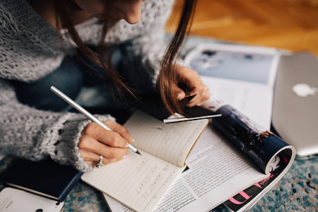 Woman in a grey sweater taking notes in an organizer thumbnail