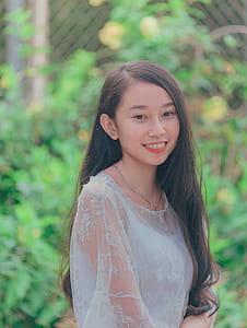 Woman Wearing White Tank Top Taking Picture Against Green Leaf Plant thumbnail