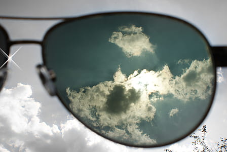 Aviator-style sunglasses facing white clouds thumbnail