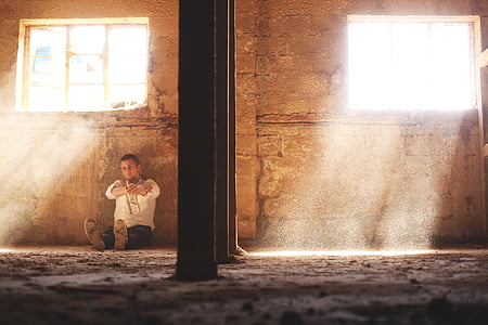 man sits beside wall thumbnail