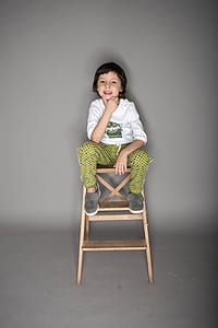 boy sitting on brown wooden chair thumbnail