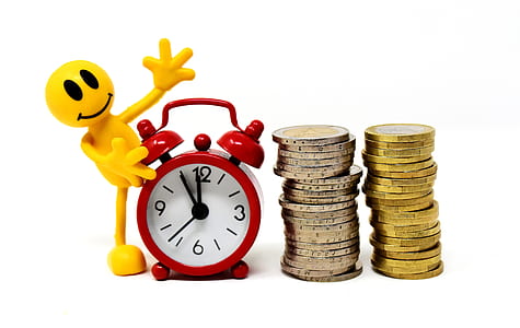 round white and red table alarm clock beside stack of coins thumbnail