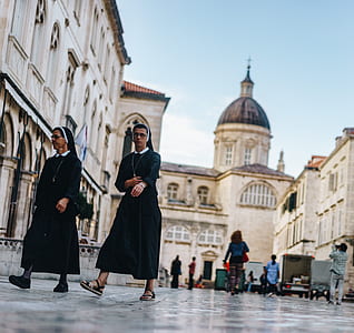 two nuns walking near concrete building thumbnail