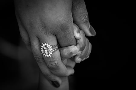 grayscale photography of adult holding toddler's hand thumbnail