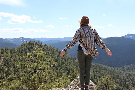 woman in gray and black dress shirt standing in front of mountains thumbnail