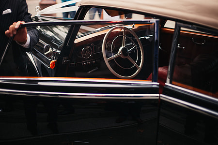 person in black suit holding the car door thumbnail