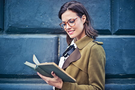 Young Woman In Brown Spectacles And Suede Pea coat Reading a Novel on the street thumbnail