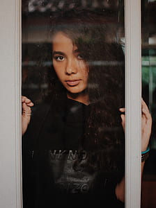 woman in black pullover hoodie leaning on clear glass door thumbnail