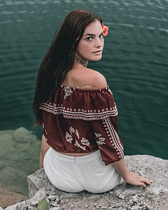 woman sitting on cliff near body of water thumbnail