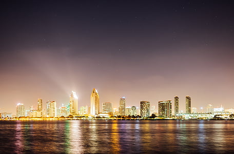 landscape photography of cityscape beside body of water at night thumbnail