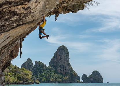person in yellow shirt climbing mountain cliff thumbnail