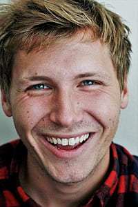 man in red and blue plaid shirt smiling thumbnail