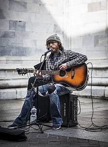 man playing guitar while sitting on stage thumbnail