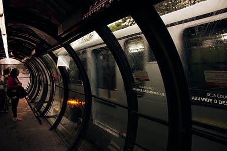 Woman Wearing Pink and Black Scoop-neck T-shirt and Black Pants Standing in Front of Train in Train Station thumbnail