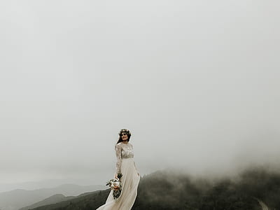 woman at the peak of the mountain wearing wedding dress thumbnail