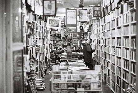 grayscale photo of man in front of wooden shelf thumbnail