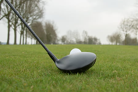golf driver beside golf ball on green grass thumbnail