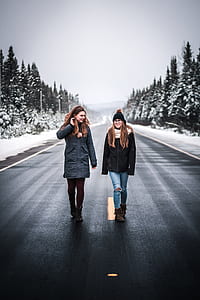 two women talking while walking on the road thumbnail