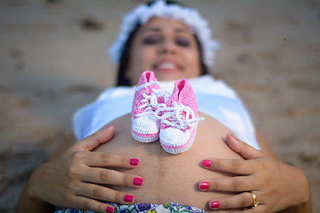 baby's crochet shoes on woman's belly thumbnail