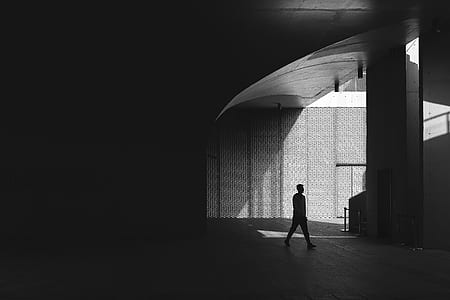 grayscale photo of man standing near wall thumbnail