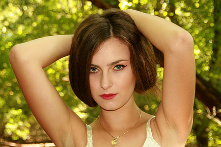 woman wearing white sleeveless top posing under tree thumbnail