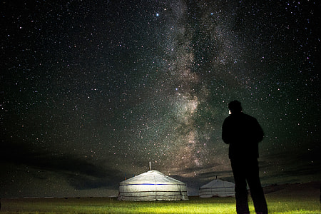 silhouette of man standing in front of canopy under stars thumbnail
